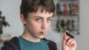 Study reveals that 5.8% of primary-school children (10–11 years) and 12.3% of secondary school children (11–16 years) have used e-cigarettes. In the image, a young boy uses an e-cigarette