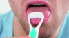 Close up of a man using a tongue scraper