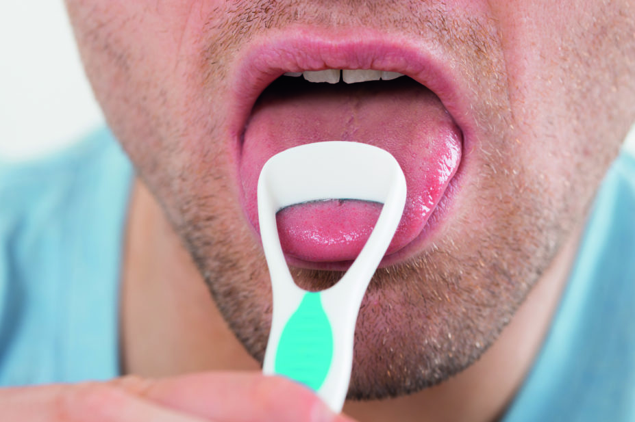 Close up of a man using a tongue scraper