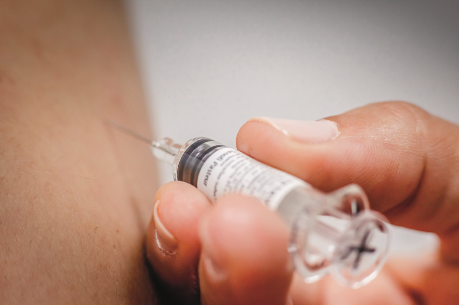 Close-up of hand giving vaccination to patient using a syringe
