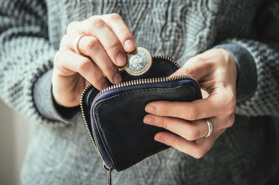 Woman putting a £1 coin in a purse