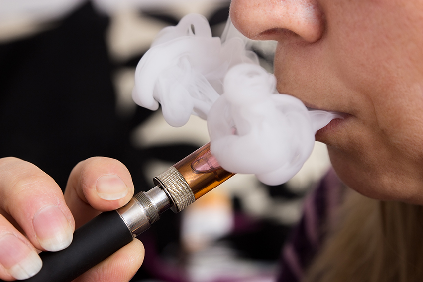 Woman eith e-cigarette exhaling a cloud of vapour