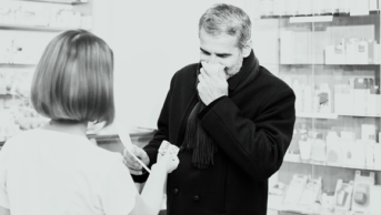 Man in pharmacy blowing his nose