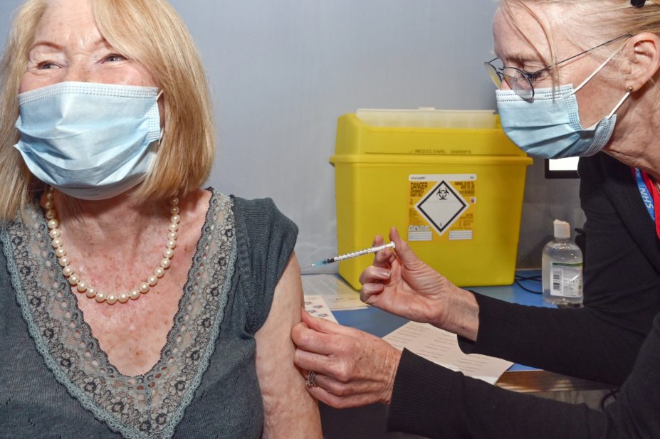 pharmacist giving older woman vaccine