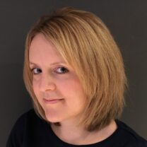 Sarah wearing a black top in front of a dark grey background