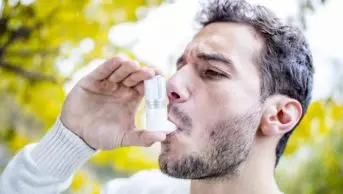 Young man using asthma inhaler