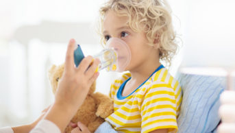 Adult holding inhaler on child's face