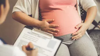 Medical professional taking notes from a pregnant woman