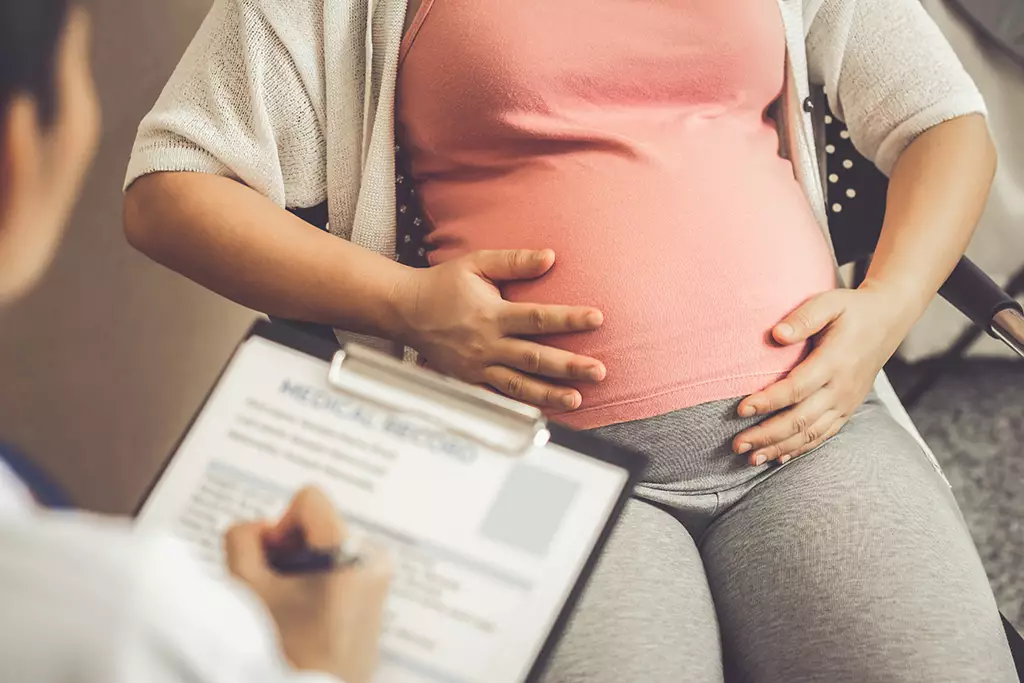 Medical professional taking notes from a pregnant woman