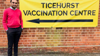 Hardik Desai next to a sign for the Ticehurst Vaccination Centre