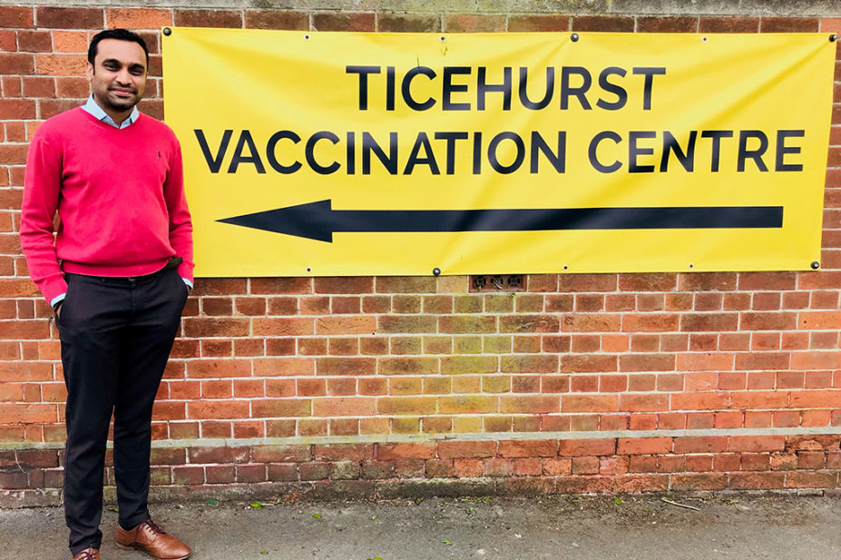 Hardik Desai next to a sign for the Ticehurst Vaccination Centre