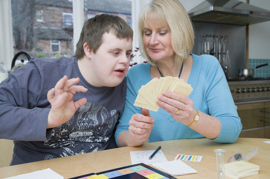 woman showing learning cards to young autistic boy