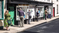 A queue maintaining safe social distancing outside the local pharmacy in the small Welsh town of Presteigne, Powys, Wales