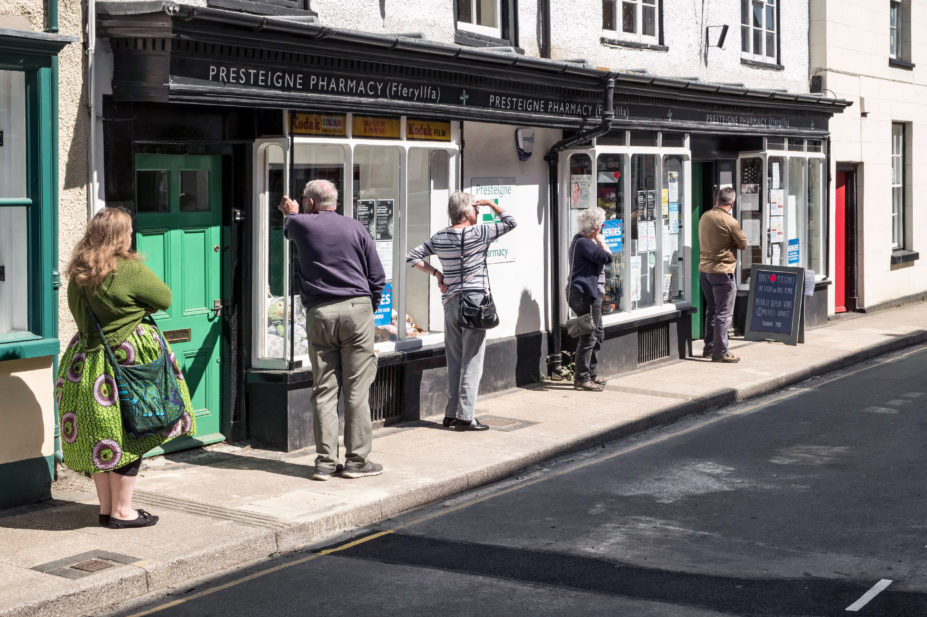 A queue maintaining safe social distancing outside the local pharmacy in the small Welsh town of Presteigne, Powys, Wales