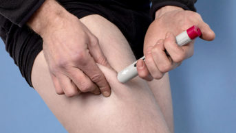 A man injecting himself in the leg with adalimumab (Humira)