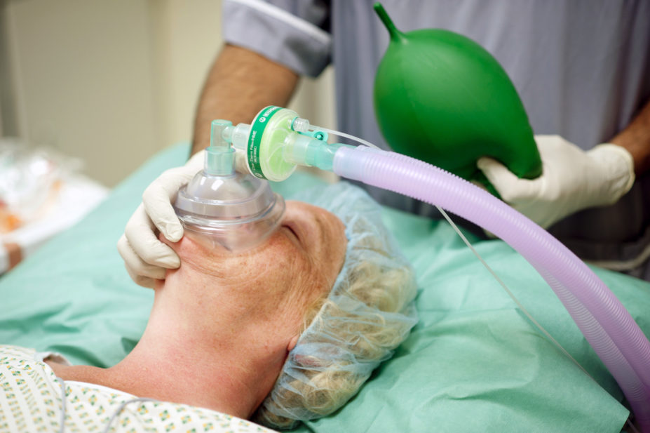 Anaesthetist using a respiration mask and handheld pump to regulate the amount of anaesthetic and oxygen being given to a patient
