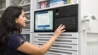 author pressing buttons on an automated medicines cabinet