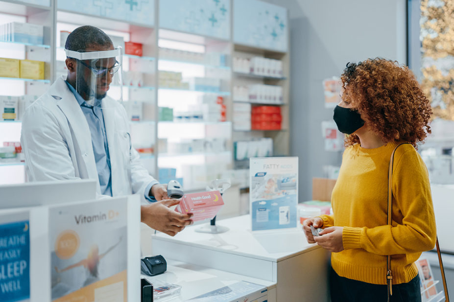 Black Pharmacist Wearing Face Shield Sells Medicine to Young Female Customer
