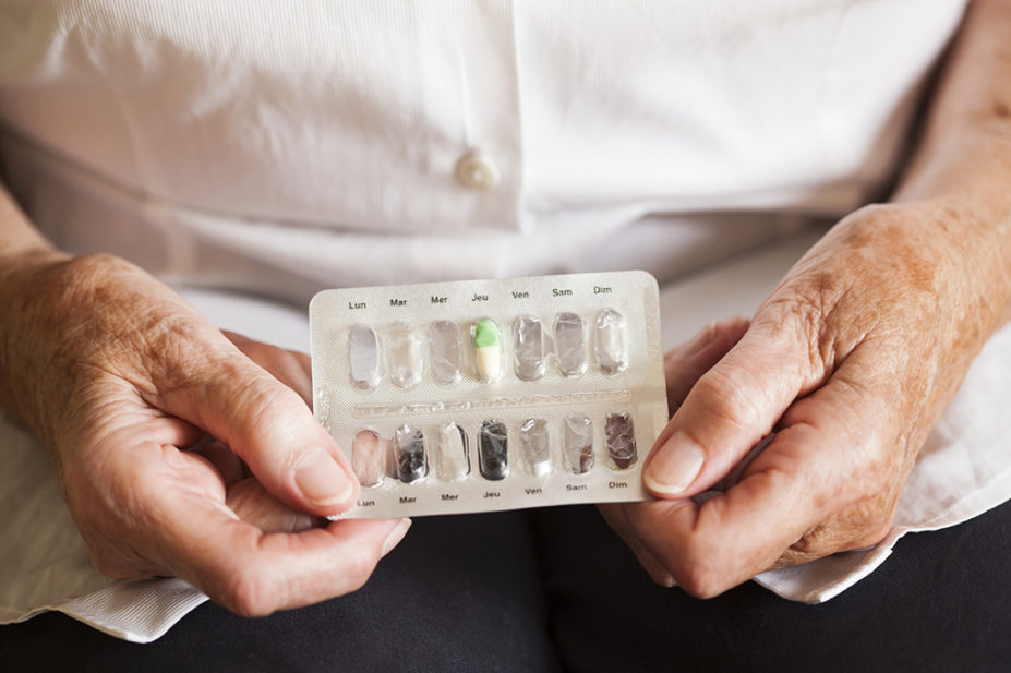 An older woman handling a blisterpack containing capsules of the antidepressant drug fluoxetine