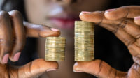 Woman holding up piles of money, pay gap concept