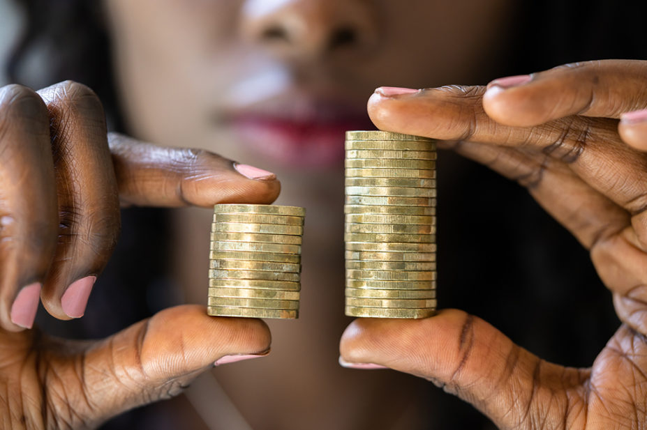 Woman holding up piles of money, pay gap concept