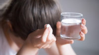 Woman holding headache medication and glass of water