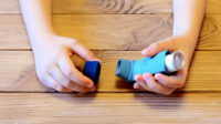 Child holds asthma inhaler in their hands