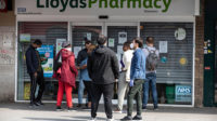 People queue outside a Lloyds Pharmacy in Tottenham, north London