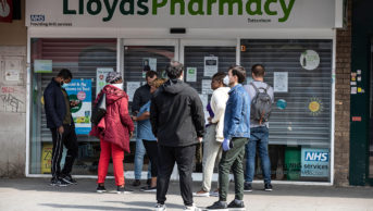 People queue outside a Lloyds Pharmacy in Tottenham, north London