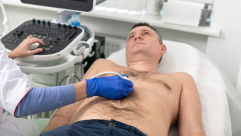 Doctor using ultrasound machine to scan heart of a male