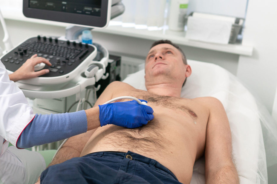 Doctor using ultrasound machine to scan heart of a male