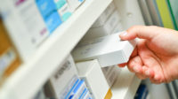 hand removing product from pharmacy shelf