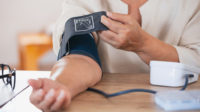 woman putting on blood pressure monitor