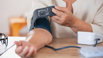 woman putting on blood pressure monitor