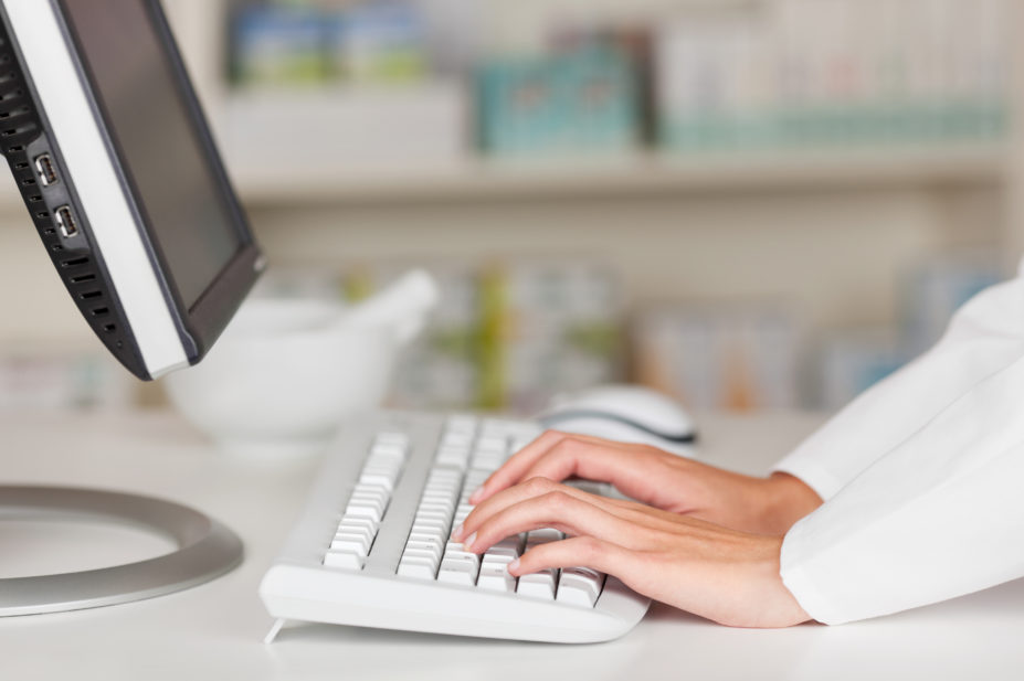 pharmacist typing on desktop computer
