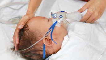 Infant being wearing oxygen mask
