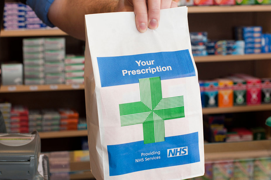 Pharmacist handing someone a prescription bag
