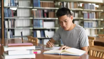 Student studying and reading book in library