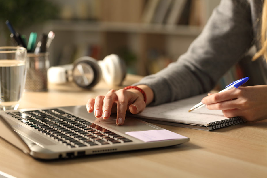 man using laptop and taking notes on notepad