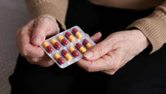 older woman holding antibiotic blister pack
