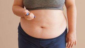 overweight woman injecting weight loss medication into abdomen