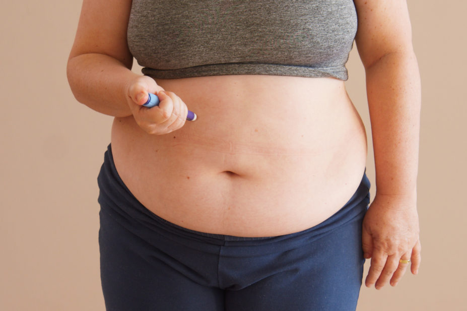 overweight woman injecting weight loss medication into abdomen