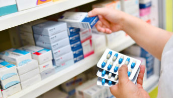pharmacist holding antibiotics and putting medicines on shelf