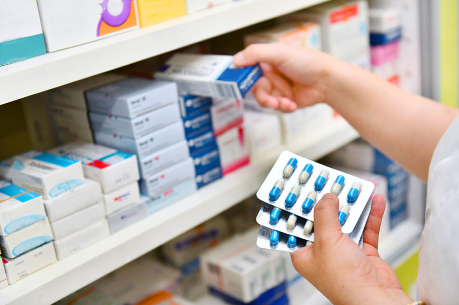 pharmacist holding antibiotics and putting medicines on shelf