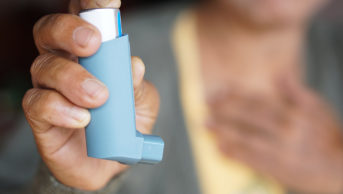 Image of someone holding a blue inhaler