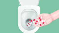 Handful of pills being disposed of down a toilet