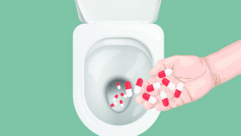 Handful of pills being disposed of down a toilet