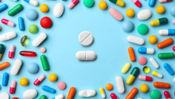 Frame made of pills on colour background
