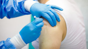 person's arm being injected by healthcare worker
