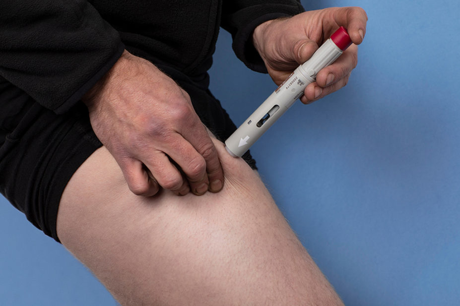 A man injecting himself in the leg with a Humira pen
